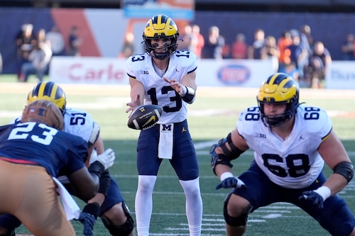 Michigan quarterback Jack Tuttle takes the snap from center in the shotgun formation during the first half of an NCAA college football game against Illinois on Saturday, Oct. 19, 2024, in Champaign, Ill.