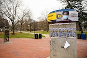 A sign showing a masked student hangs from a concrete kiosk at the entrance to the Diag on the University of Michigan campus in Ann Arbor on Tuesday, Dec. 8, 2020.