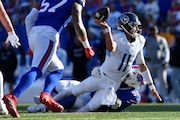 Tennessee Titans quarterback Mason Rudolph (11) looks to pass as he is tackled by Buffalo Bills defensive tackle DaQuan Jones (92) during the second half of an NFL football game in Orchard Park, N.Y., Sunday, Oct. 20, 2024. (AP Photo/Adrian Kraus)