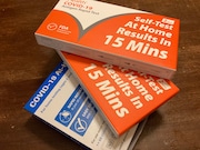A stack of free COVID-19 tests delivered by the U.S. Postal Services from the federal government sits on a kitchen table in Michigan.