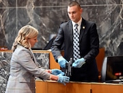 Oakland County Prosecutor Karen McDonald takes the gun, described as the murder weapon, from Special Agent Brett Brandon during the James Crumbley trial, in the Oakland County Courtroom on Monday, March 11, 2024, in Pontiac, Mich. He is accused of failing to secure a gun at home and ignoring signs of his son Ethan Crumbley's mental distress. (Daniel Mears/Detroit News via AP, Pool) AP